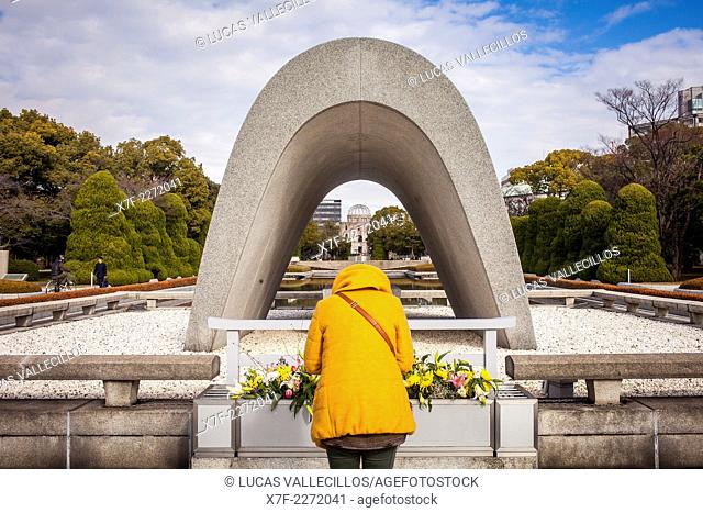Praying, Cenotaph for the Atomic bomb victims, in background Atomic Bomb Dome, Peace Park, Hiroshima, Japan