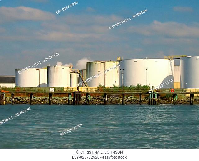 A photograph of storage tanks located near a waterway