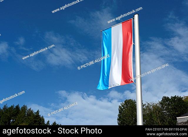13 October 2023, Luxembourg, Vianden: The national flag of the Grand Duchy of Luxembourg flies in the wind. The tricolor consists of three equal horizontal...
