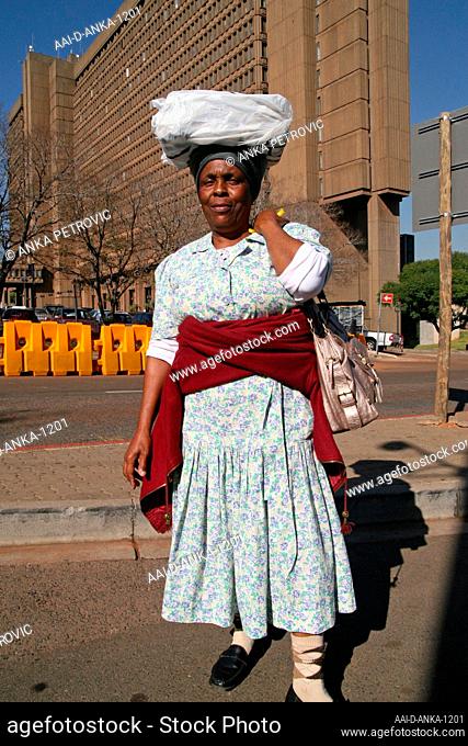 African lady carrying load on head next to building, Braamfontein, Johannesburg, Gauteng, South Africa