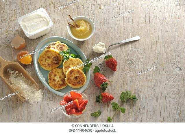 Sirniki (Russian quark pancakes) with apple sauce and strawberries