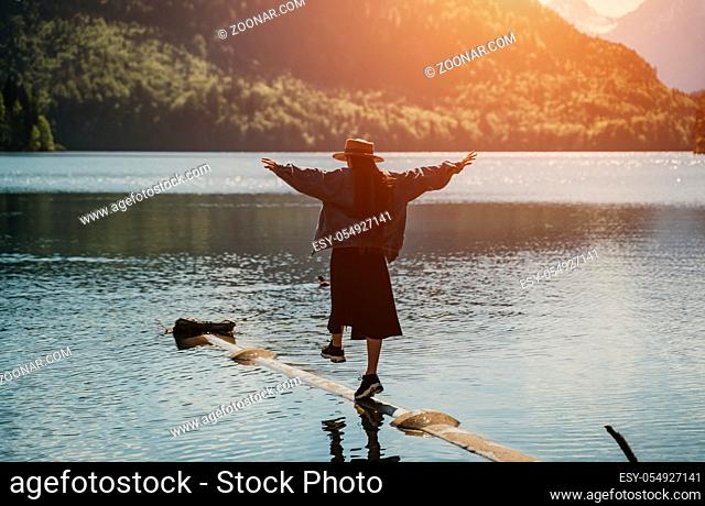 The girl in the dress and hat of the lake in the mountains to hold balance