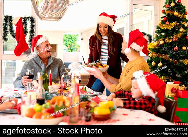 Caucasian multi generation family wearing santa hats having christmas meal