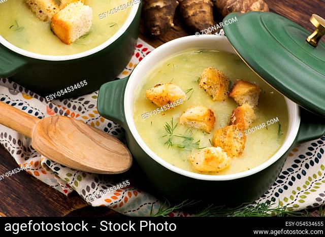 Creamy Jerusalem artichoke soup on wooden background