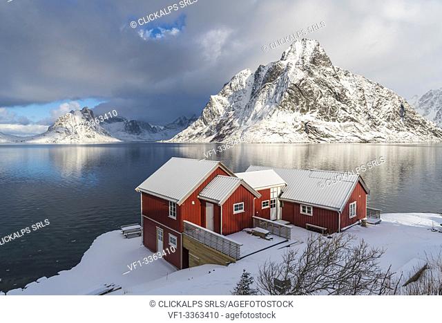 Traditional 'rorbu' houses with Olstinden peak in the background in winter. Reine, Lofoten district, Nordland county, Northern Norway, Norway