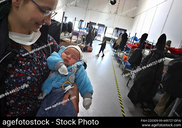 09 March 2022, Bavaria, Augsburg: A refugee woman from Ukraine holds her four-week-old baby in her arms in the dormitory of the ANKER Center