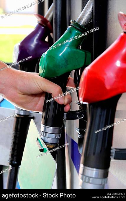 Petrol or gasoline pump nozzles with hand on the green one