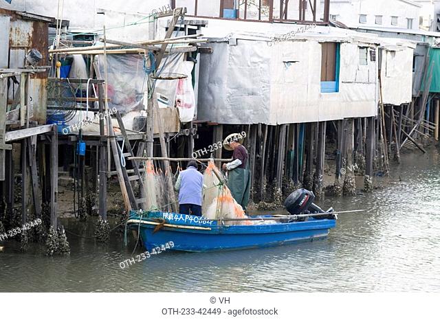Fishermen arranging the fish net on a boat by the stilt houses, Tai O, Lantau Island, Hong Kong