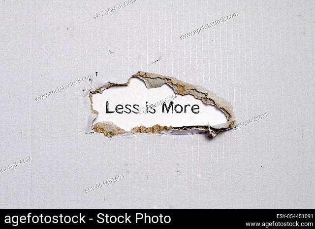 The word less is more appearing behind torn paper