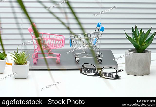 empty miniature shopping carts on white desk. Seasonal sale, online shopping