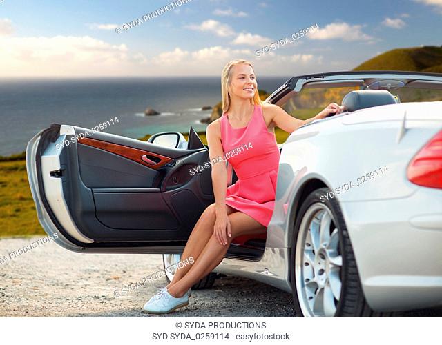 woman posing in convertible car over big sur coast