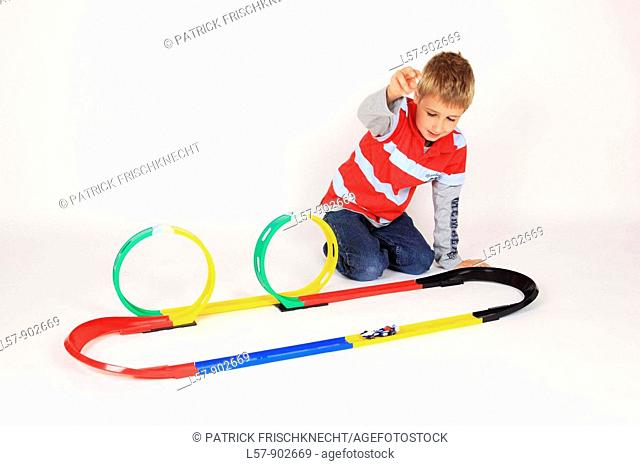 boy playing with racing car on floor, white background, Studio, Switzerland