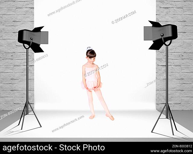 Little girl in photo studio room with white cloth and spotlights