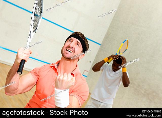 Handsome squash player man expressing astonishment after great battle in squash with his best friend on court