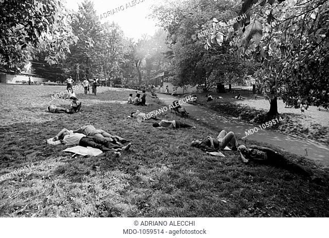 Festa dell'Unità. People attending Festa dell'Unità in Parco Sempione relaxing lying down on the grass. Milan, September 1979