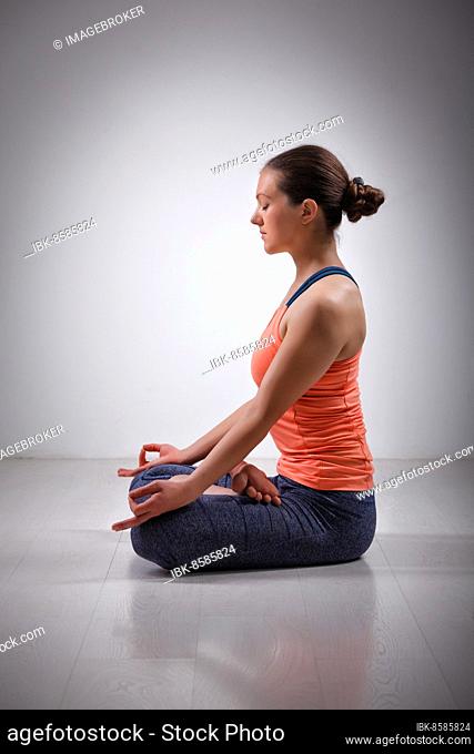 Beautiful fit yogini woman meditating in yoga asana Padmasana (Lotus pose) cross legged position for meditation with Chin Mudra