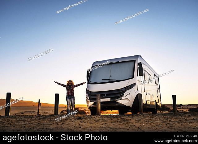 Woman standing outstretching arms and enjoying freedom and travel lifestyle with modern camper van. Alternative home and travel lifestyle for happy people