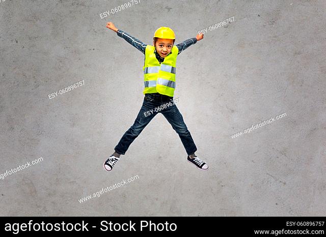 boy in safety vest and construction helmet jumping