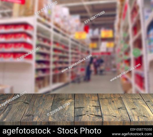Vintage wooden boards with view to shelves of supermarket. Table top with shopping place. Vintage boards with products on shelves of shop