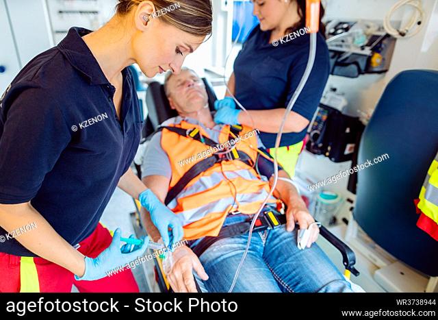 Emergency doctor woman giving drop injection to injured man in ambulance