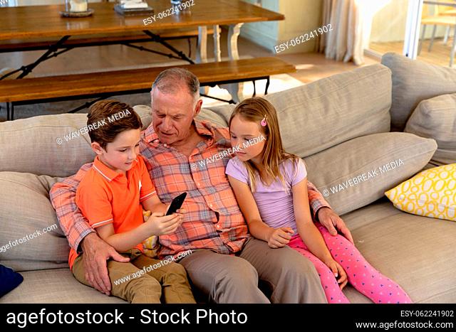 Grandfather and grandchildren at home in the living room