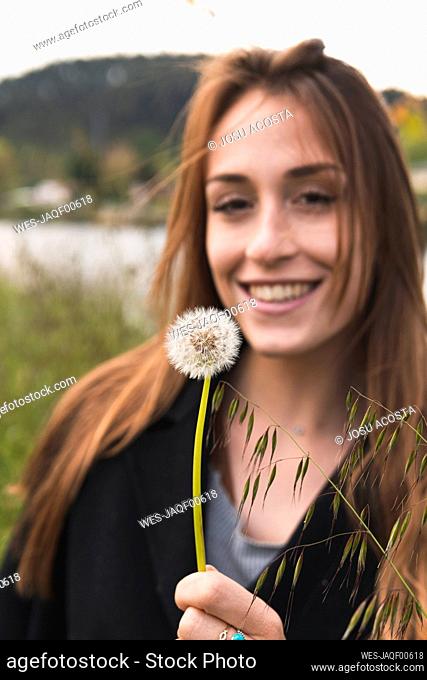 Beautiful woman smiling while looking at blowball