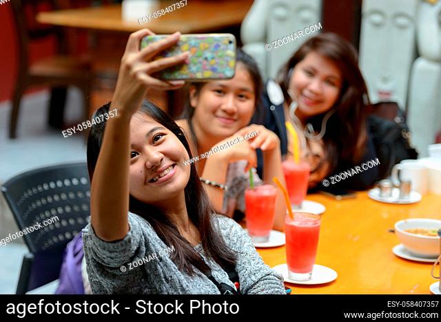 Portrait group of young Asian women as friends hanging out and relaxing together at the coffee shop outdoors