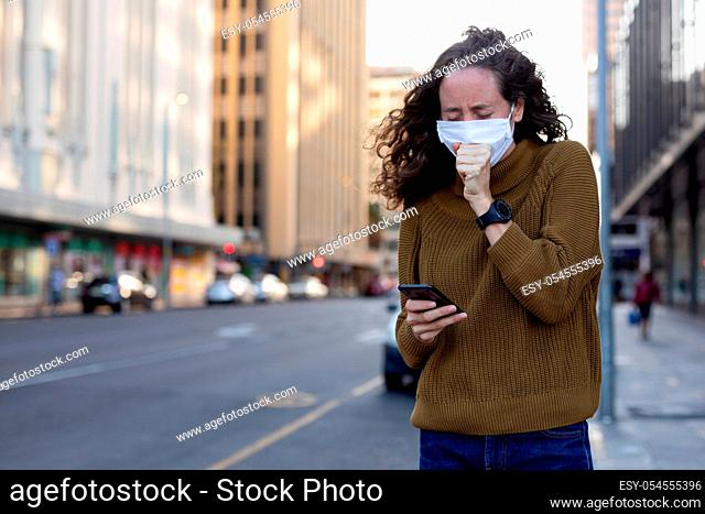 Caucasian woman wearing a protective mask and coughing out in the streets