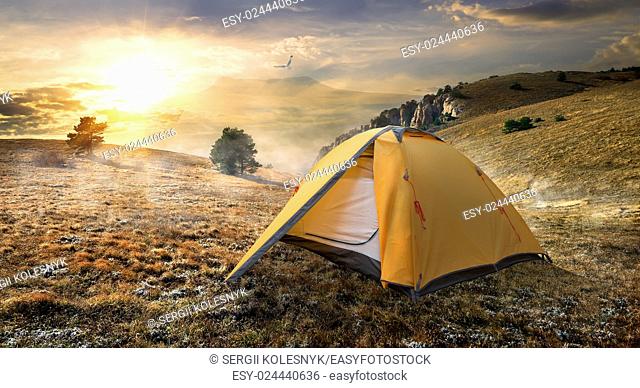 Tourist tent in autumn mountains at sunrise