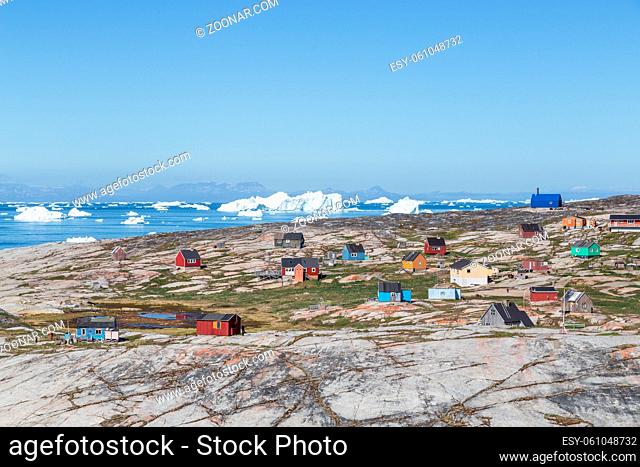 Rodebay, Greenland - July 08, 2018: Colorful wooden houses with icebergs in the background. Rodebay, also known as Oqaatsut is a fishing settlement north of...