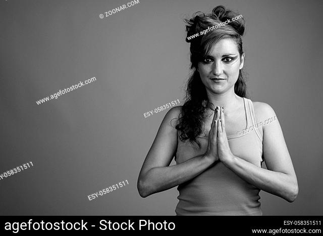 Studio shot of beautiful woman with hair tied and makeup against gray background in black and white