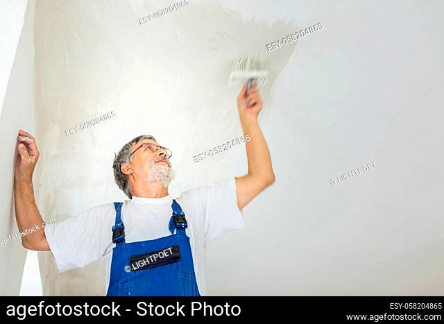 Painter man at work with a paint bucket, wall painting concept