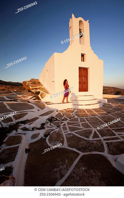 Woman posing in front of a chapel at the top of the hill in Chora, Ios, Cyclades Islands, Greek Islands, Greece, Europe