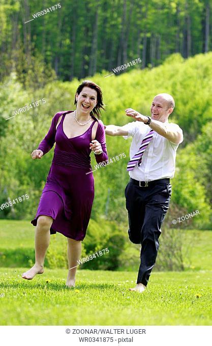 a man and a woman running in a meadow