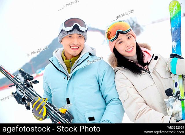 Ski resort happy young couples holding equipment