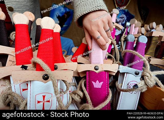 28 May 2022, Saxony-Anhalt, Harzgerode: Wooden swords lie at a stand with children's toys at the knights' festival at Falkenstein Castle