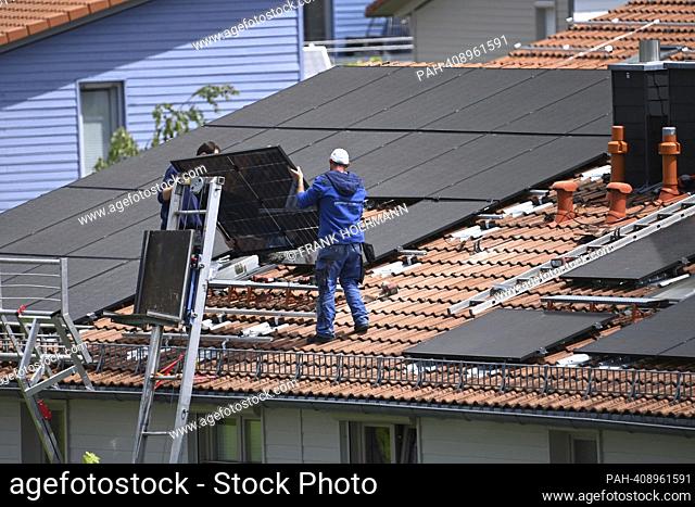 Detached house with photovoltaic system: workers installing solar panels on a house roof. Solar cells, solar modules, residential building, solar power