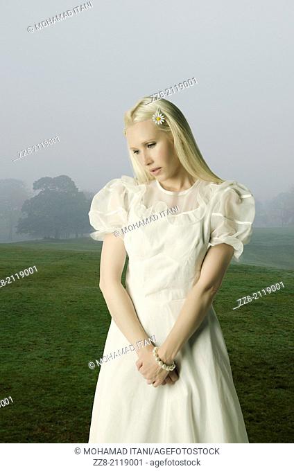 Sad woman standing in a misty field