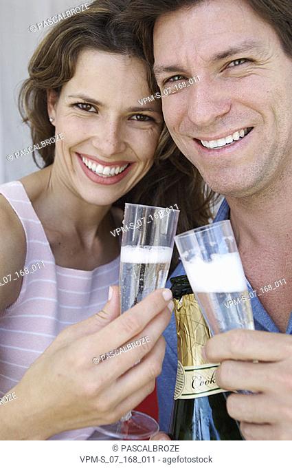 Portrait of a young couple smiling and holding champagne flutes
