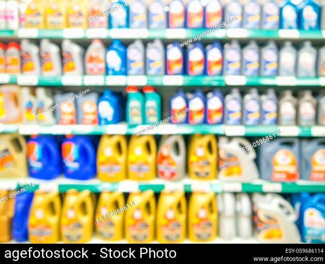 Blurred colorful motor oil bottles on shelves in supermarket as background