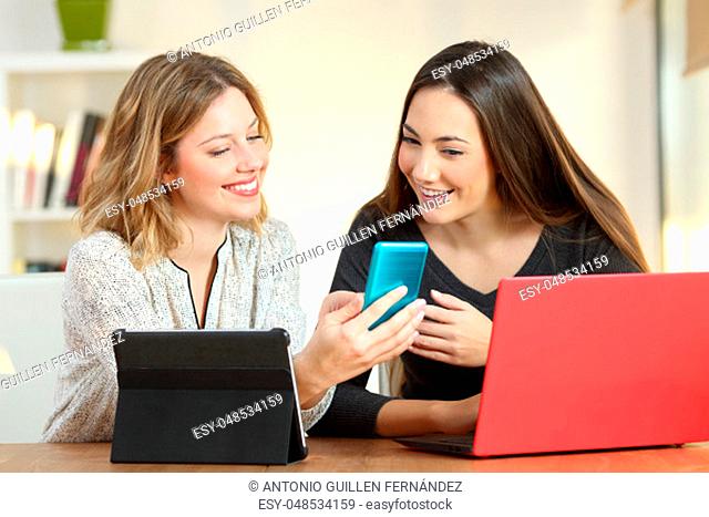 Two friends using multiple devices and sharing online content at home