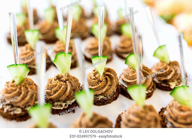 food, junk-food, catering and unhealthy eating concept - close up of canape with paste on serving tray