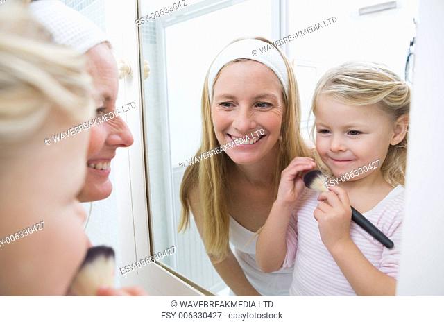 Happy mother and daughter playing with make up at home in the bathroom