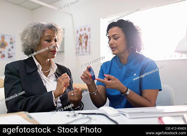 Female doctor teaching diabetic patient how to use glucometer in doctors office