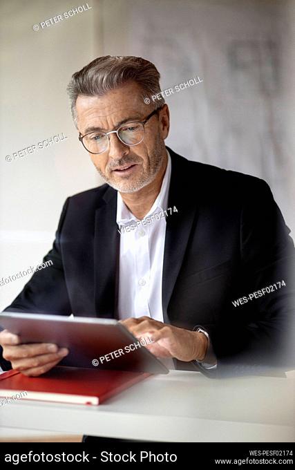 Businessman wearing eyeglasses using digital tablet while working at home