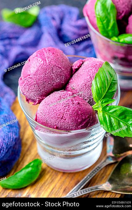 Artisanal blueberry ice cream with basil in glasses on a wooden serving board, selective focus. Summer dessert