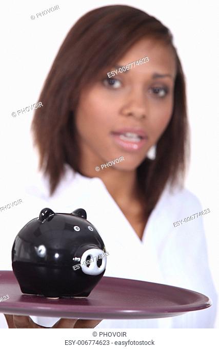Woman carrying piggy-bank on tray