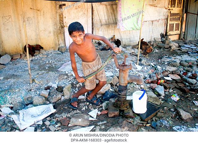Boy pumping water from hand pump ; Malvani slum ; Malad ; Bombay Mumbai ; Maharashtra ; India NO MR