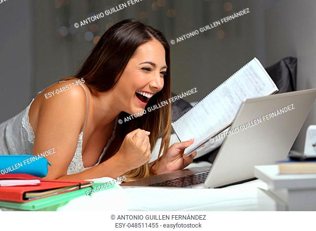 Excited student reading good news online in a laptop lying on a bed in the night at home