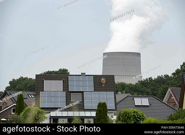 View of the Emsland nuclear power plant with cooling tower, in the foreground a housing estate, on the roofs are solar modules, photovoltaic systems